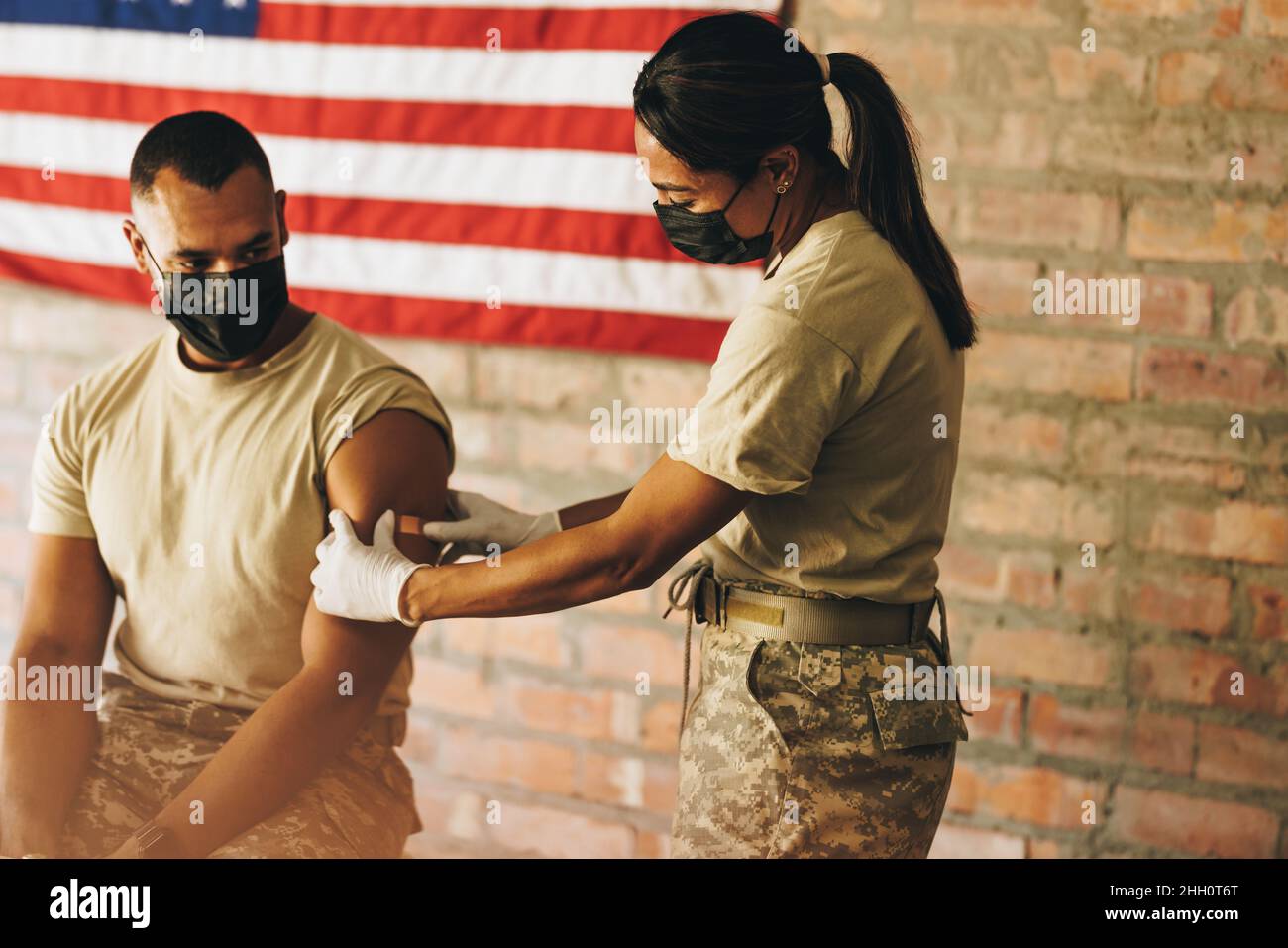 Krankenschwester, die im Militärkrankenhaus ein Pfand auf den Arm eines Soldaten legt. Amerikanischer Arzt, der einen medizinischen Klebstoff nach Verabreichung einer Dosis des Kohlenstoffs aufgibt Stockfoto