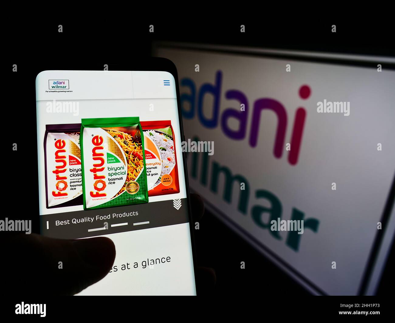 Person, die Smartphone mit Website des indischen Lebensmittelunternehmens Adani Wilmar Limited auf dem Bildschirm vor dem Logo hält. Konzentrieren Sie sich auf die Mitte des Telefondisplays. Stockfoto