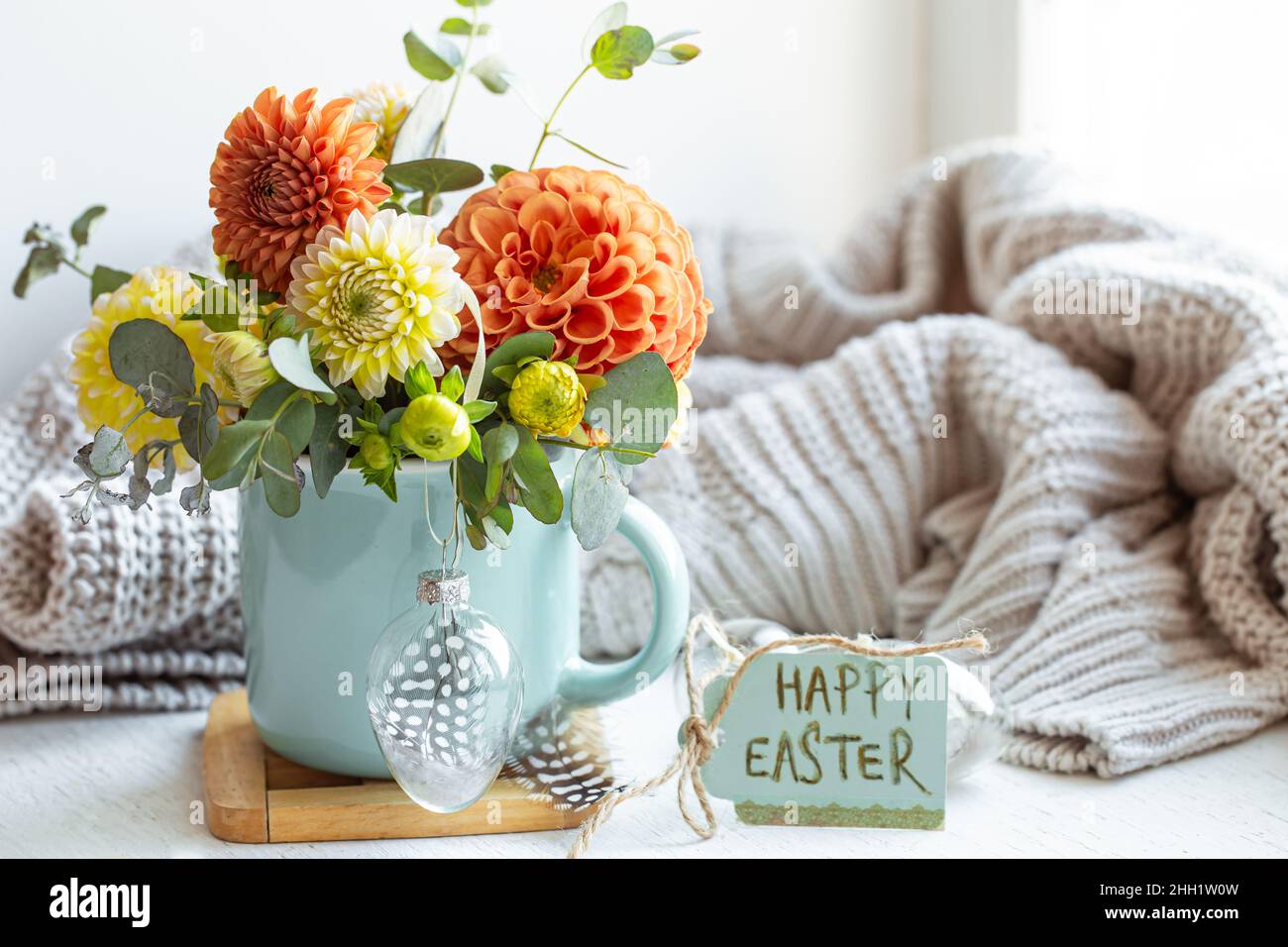 Osterkomposition mit einem Blumenstrauß und einem gestrickten Element. Stockfoto