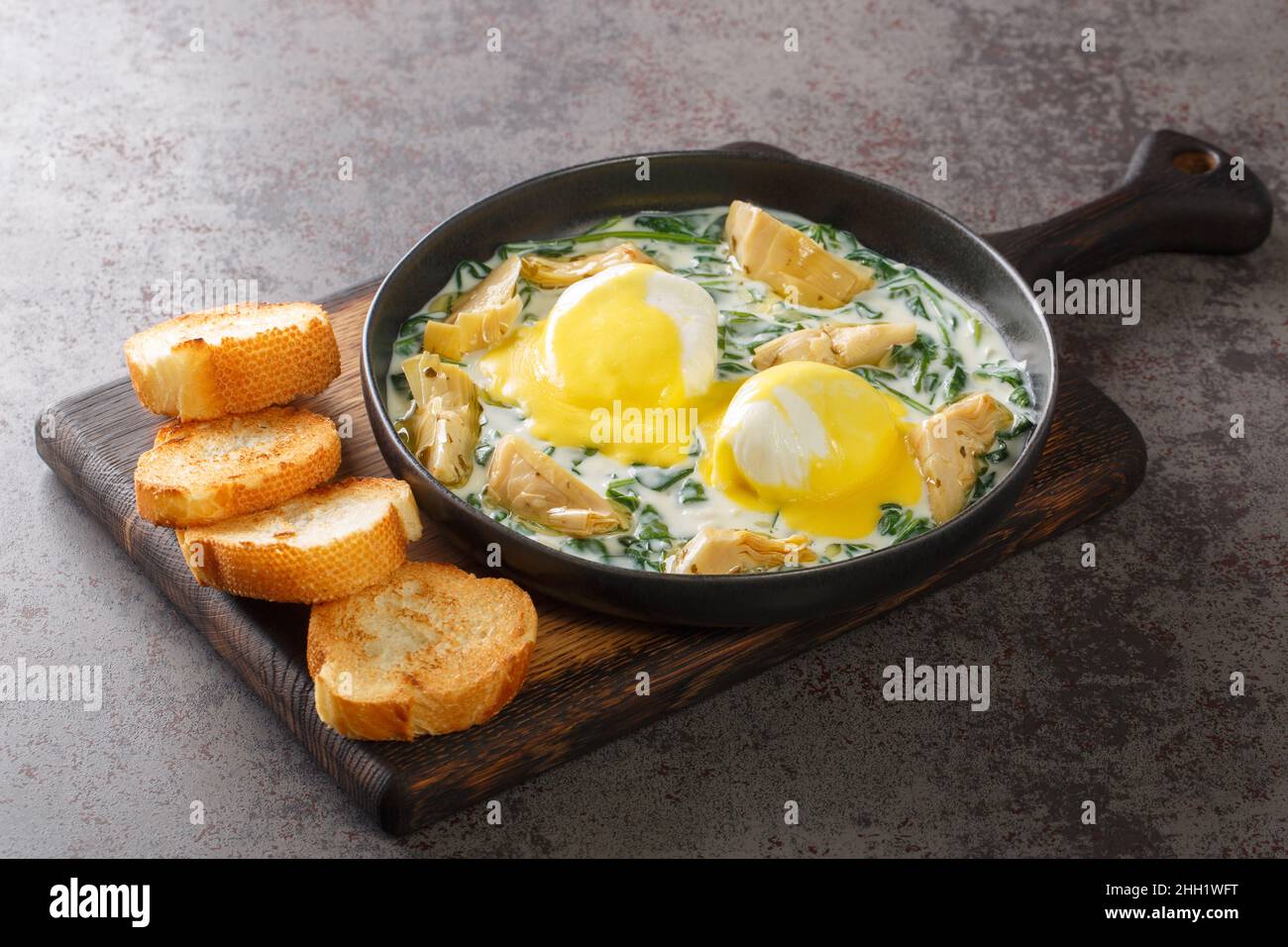 Eier im New Orleans-Stil Sardou pochierte Eier mit Artischocke, Spinat und Hollandaise aus nächster Nähe auf dem Teller auf dem Tisch. Horizontal Stockfoto