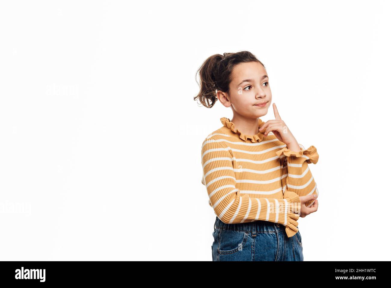Nachdenkliches Mädchen, das über etwas nachdenkt, während es über einem isolierten Hintergrund steht. Stockfoto