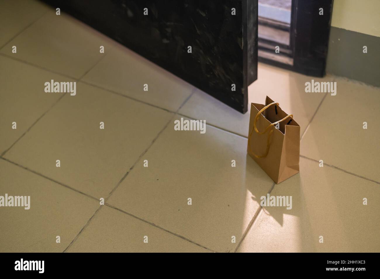In der Lobby vor der Haustür der Wohnung steht eine Öko-Papiertüte. Kontaktlose Lebensmittelversorgung für die Epidemie. Der Kurier hat ein Online-Formular verlassen Stockfoto