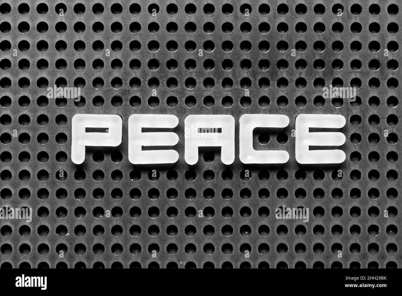 Weißer Buchstabe im Wort Frieden auf schwarzem pegboard Hintergrund Stockfoto