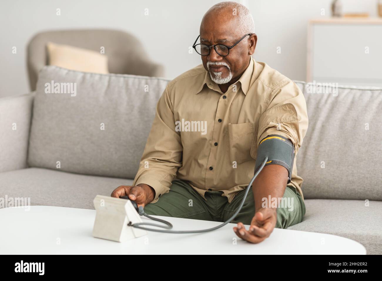 Senior Black Man Misst Arteriellen Blutdruck Sitzend Zu Hause Stockfoto