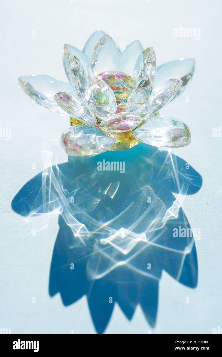 Wunderschöne Lotusblume aus Kristall auf einem blauen sonnigen Tisch. Stockfoto