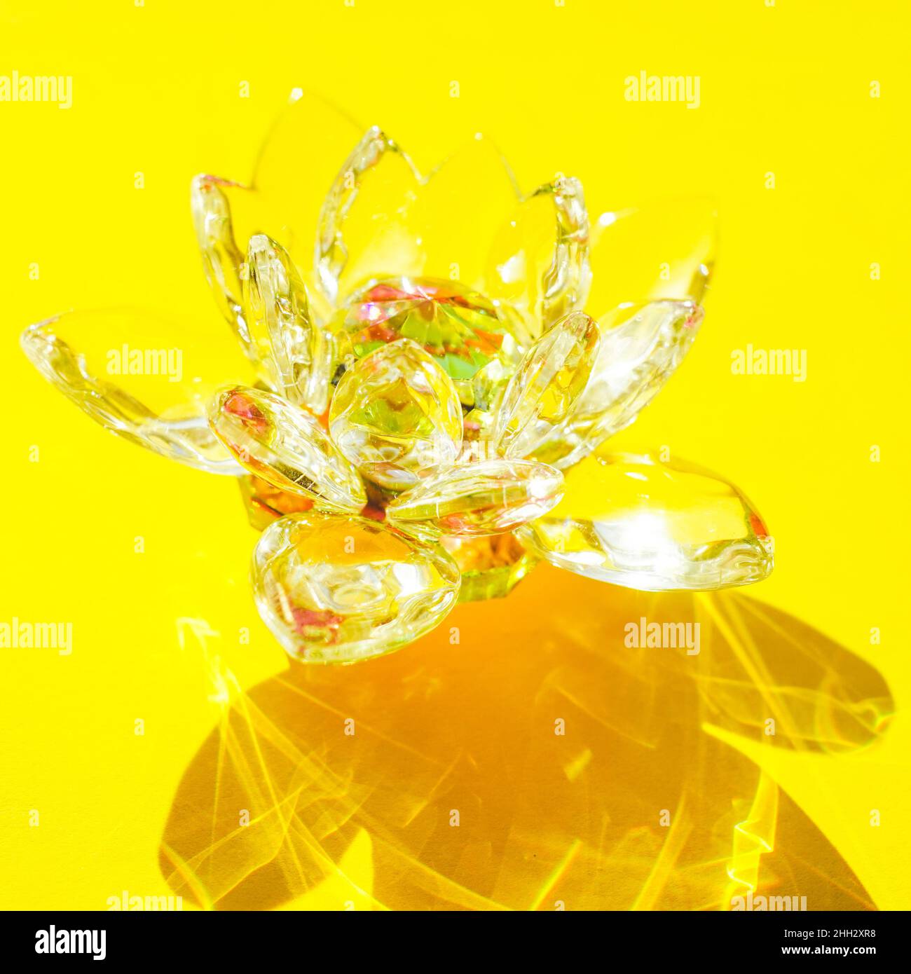 Wunderschöne Lotusblume aus Kristall auf einem gelben sonnigen Tisch. Stockfoto
