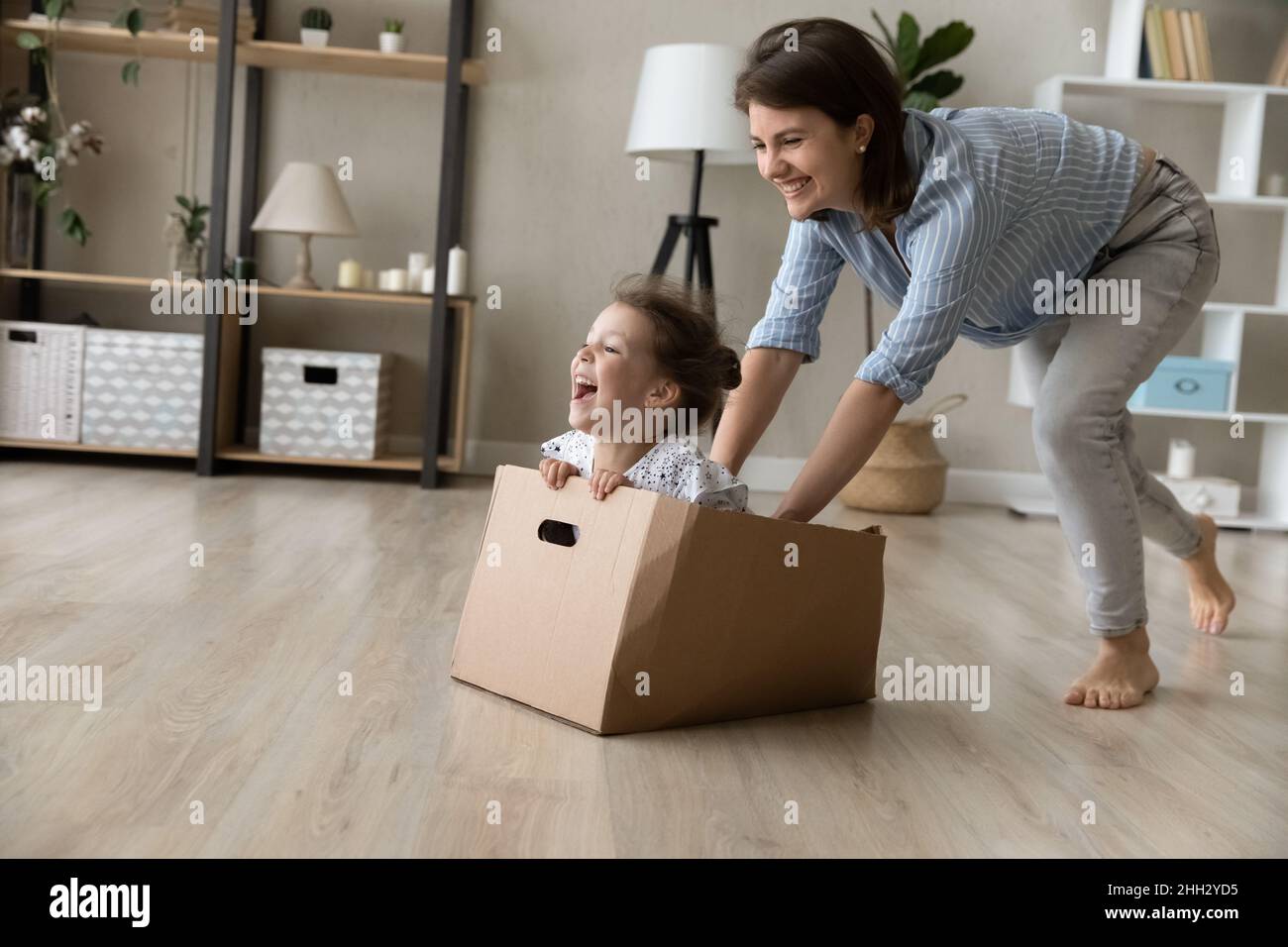 Fröhliche junge Mutter, die zu Hause mit der kleinen Tochter spielt. Stockfoto