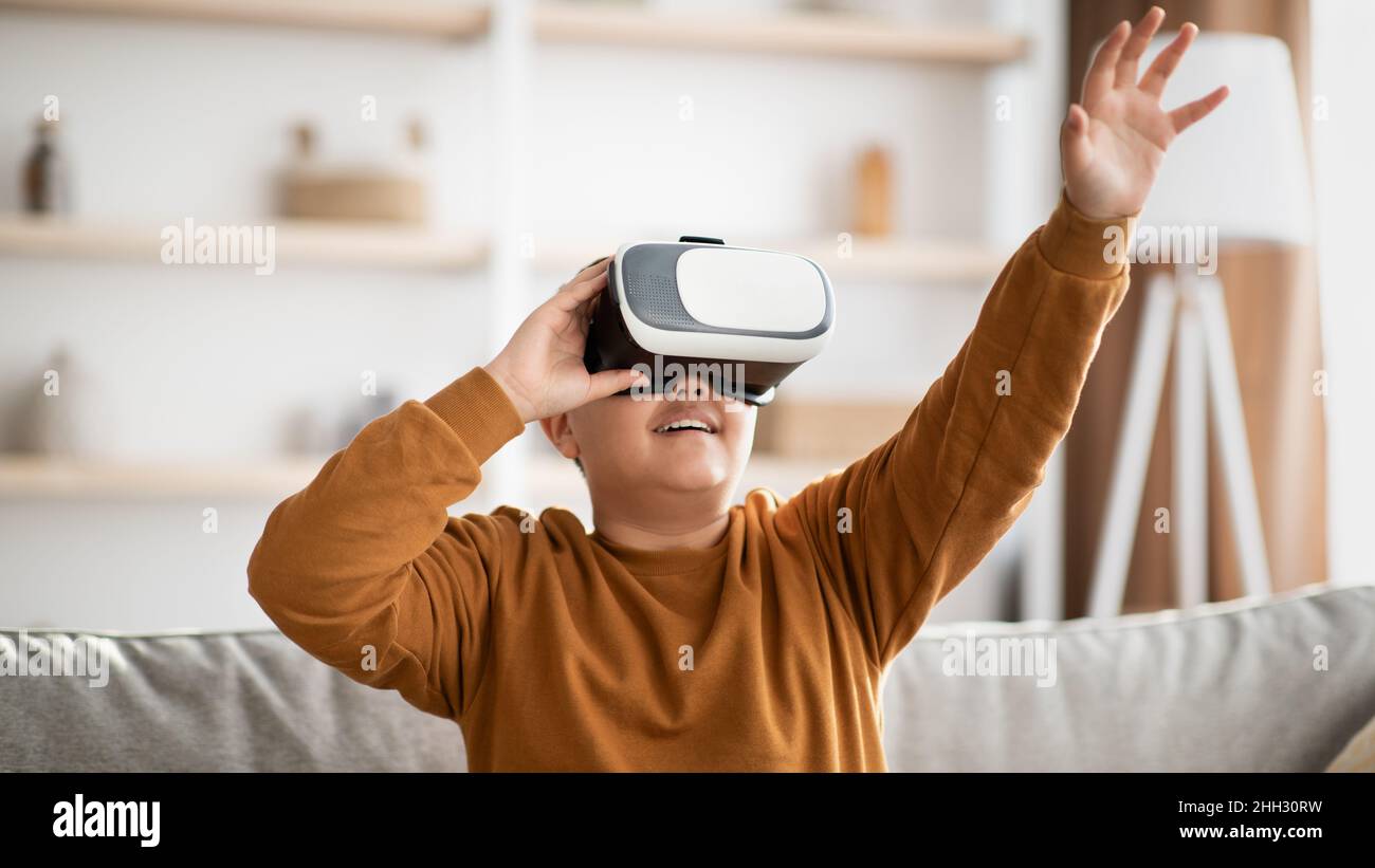 Fröhlicher Teenager, der VR-Brille verwendet und etwas Unsichtbares berührt Stockfoto