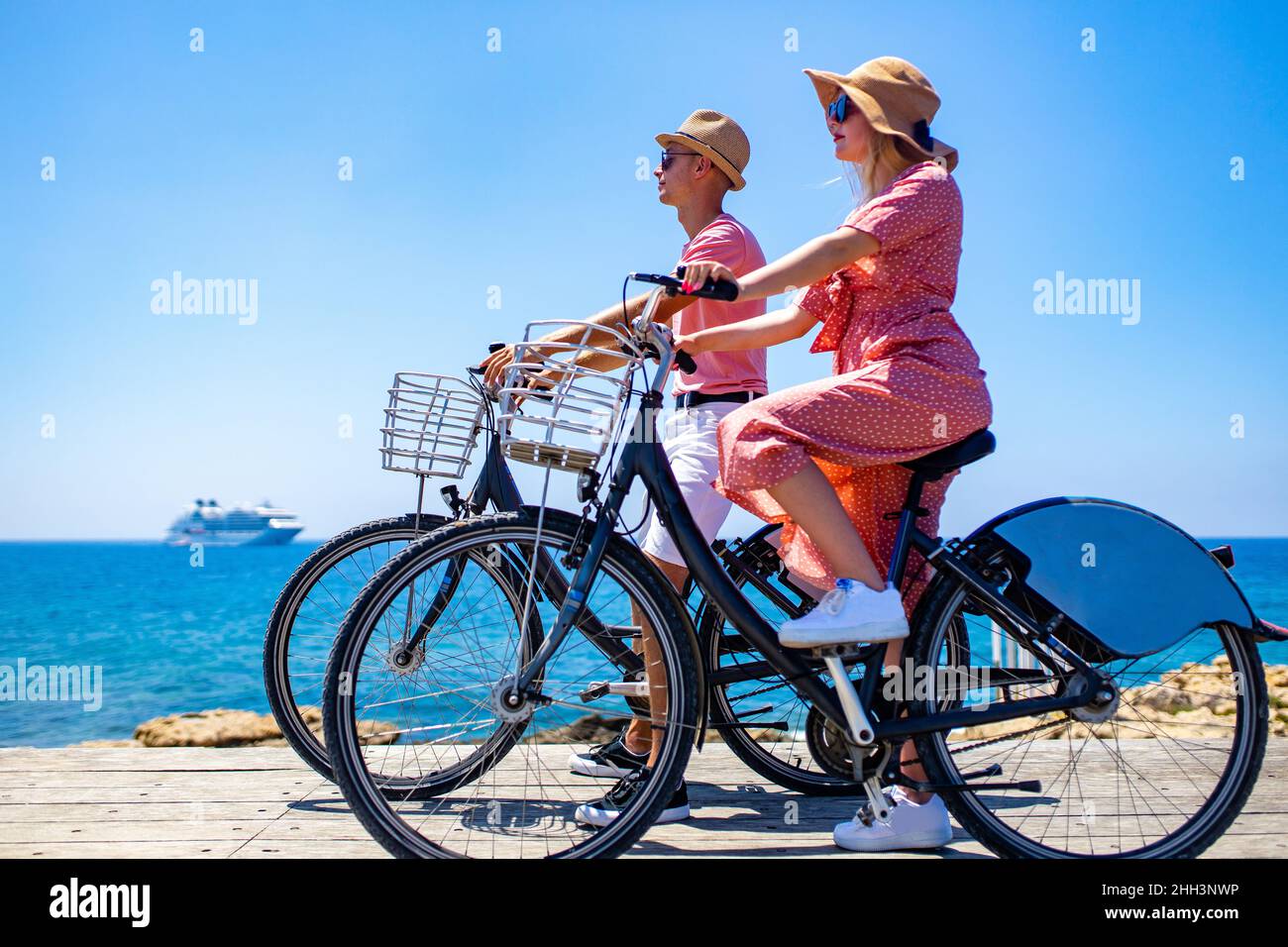 Fröhliche Erwachsene Menschen fröhliches Paar genießen die Outdoor-Freizeitbeschäftigung auf dem Fahrrad am Meer Stockfoto