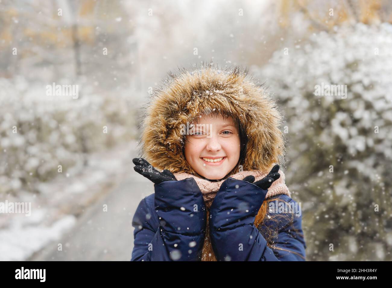 Nettes Mädchen fangen Schneeflocken Spaß im Freien in einem ersten Schnee. Stockfoto