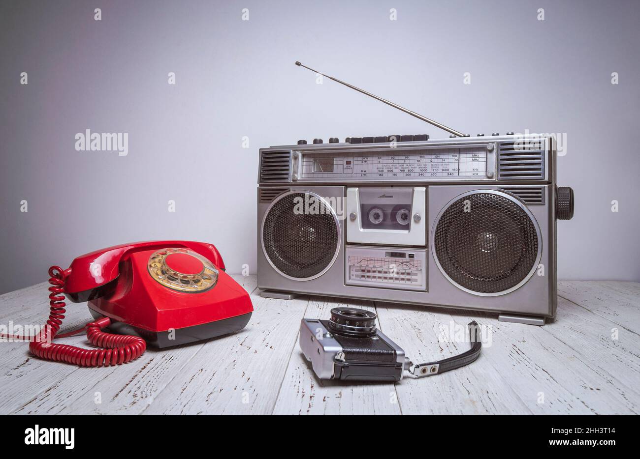 Ein alter Retro-Kassettenrekorder, Telefon und Kamera stehen auf einem Holztisch. Vintage gefiltertes altes Foto. Stockfoto