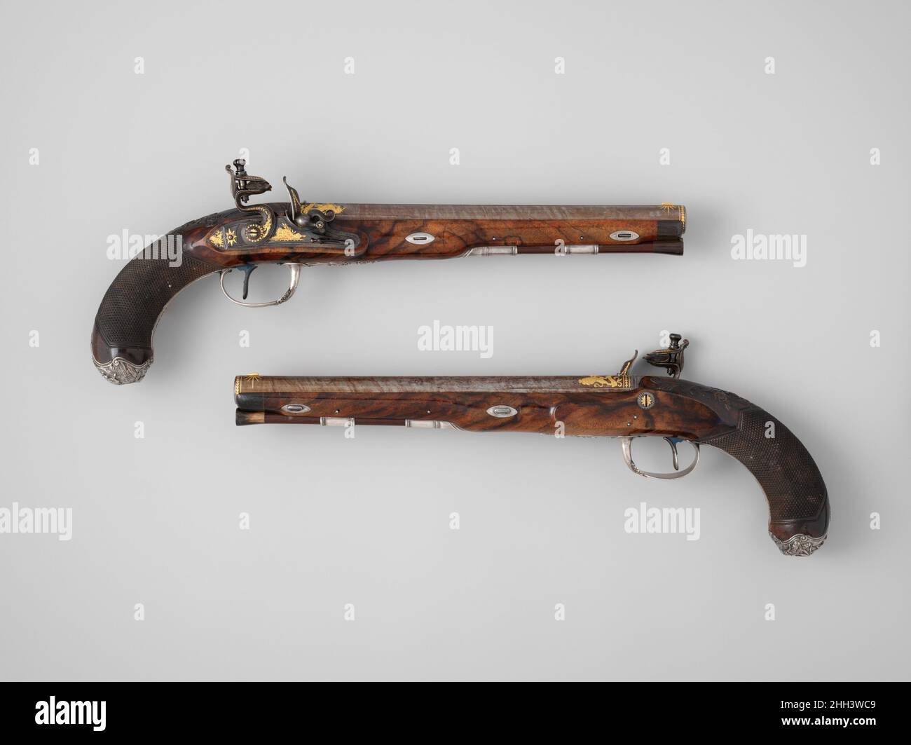Ein Paar Feuerstockpistolen des Prinzen von Wales, später George IV. (1762–1830), mit Etui und Accessoires, die für 1787–88 Durs Egg gekennzeichnet sind, geschmackvoll verziert mit niedrig reliefartigen silbernen Pommeln, die eine Kavalleriekampfszene darstellen, goldeingelegten Fässern und Schlössern mit den königlichen Waffen, Diese Pistolen wurden für George IV, als Prince of Wales (1762–1830), von Durs Egg, einem der talentiertesten und einflussreichsten Waffenhersteller seiner Zeit, angefertigt und sind luxuriös geschnitzte, figurierte Walnussholzschäfte. Das Paar ist ein Beispiel für Egg’s feinste Arbeit. Egg’s Werkstatt produzierte die Pistolen für den Prinzen, gerade als Egg den Gipfel erreichte Stockfoto