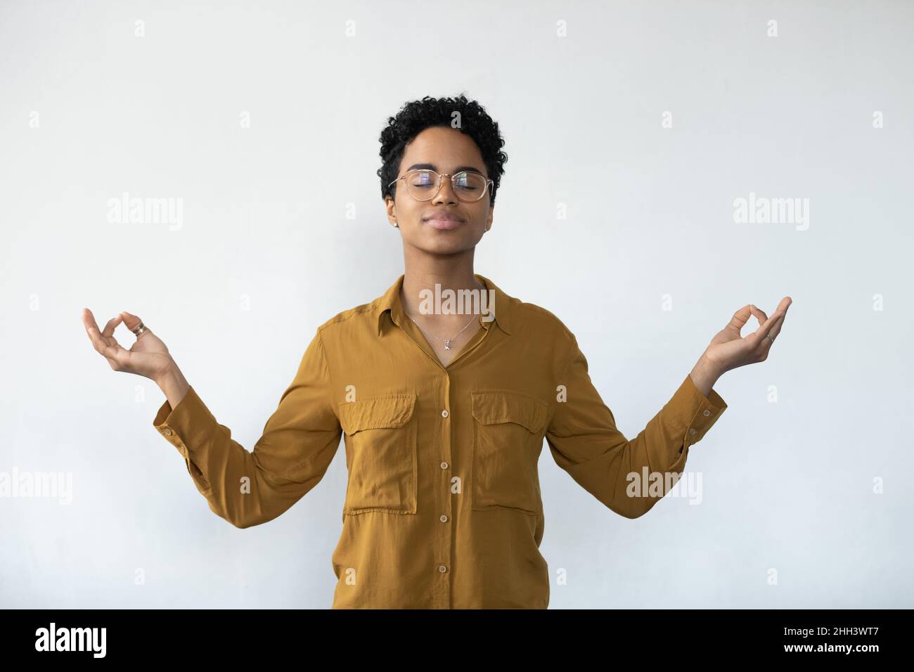Friedliches afroamerikanisches Mädchen in Brille, meditiert mit Zen-Händen Stockfoto