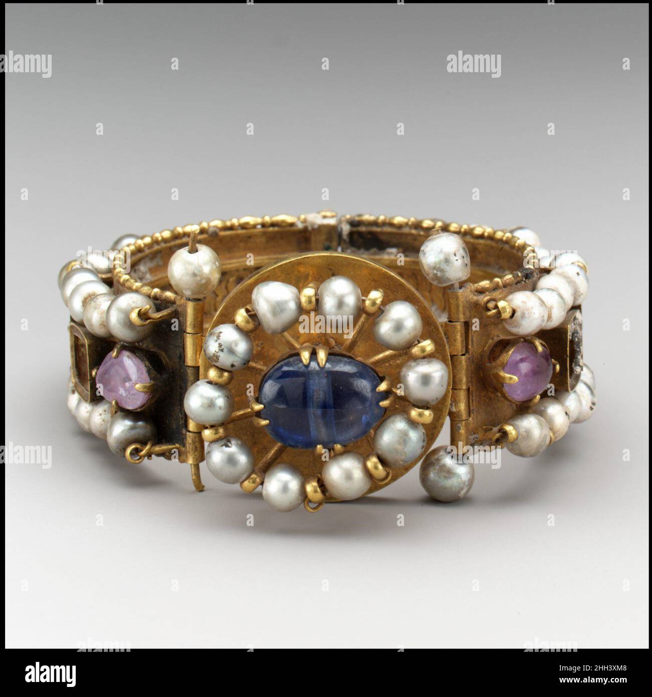 Jeweled Bracelet (One of Pair) 500–700 Byzantine Diese aufwendig verzierten Armbänder haben reich verzierte Außenflächen und fein detaillierte Opus-Interrasile-Muster auf ihren Innenräumen. Die leuchtende Schönheit der Perlen wurde in der byzantinischen Welt hoch geschätzt. Armband mit Schmuck (ein Paar). Byzantinisch. 500–700. Gold, Silber, Perlen, Amethyst, Saphir, Glas, Quarz. Hergestellt wahrscheinlich in Konstantinopel. Metallarbeiten-Gold Stockfoto