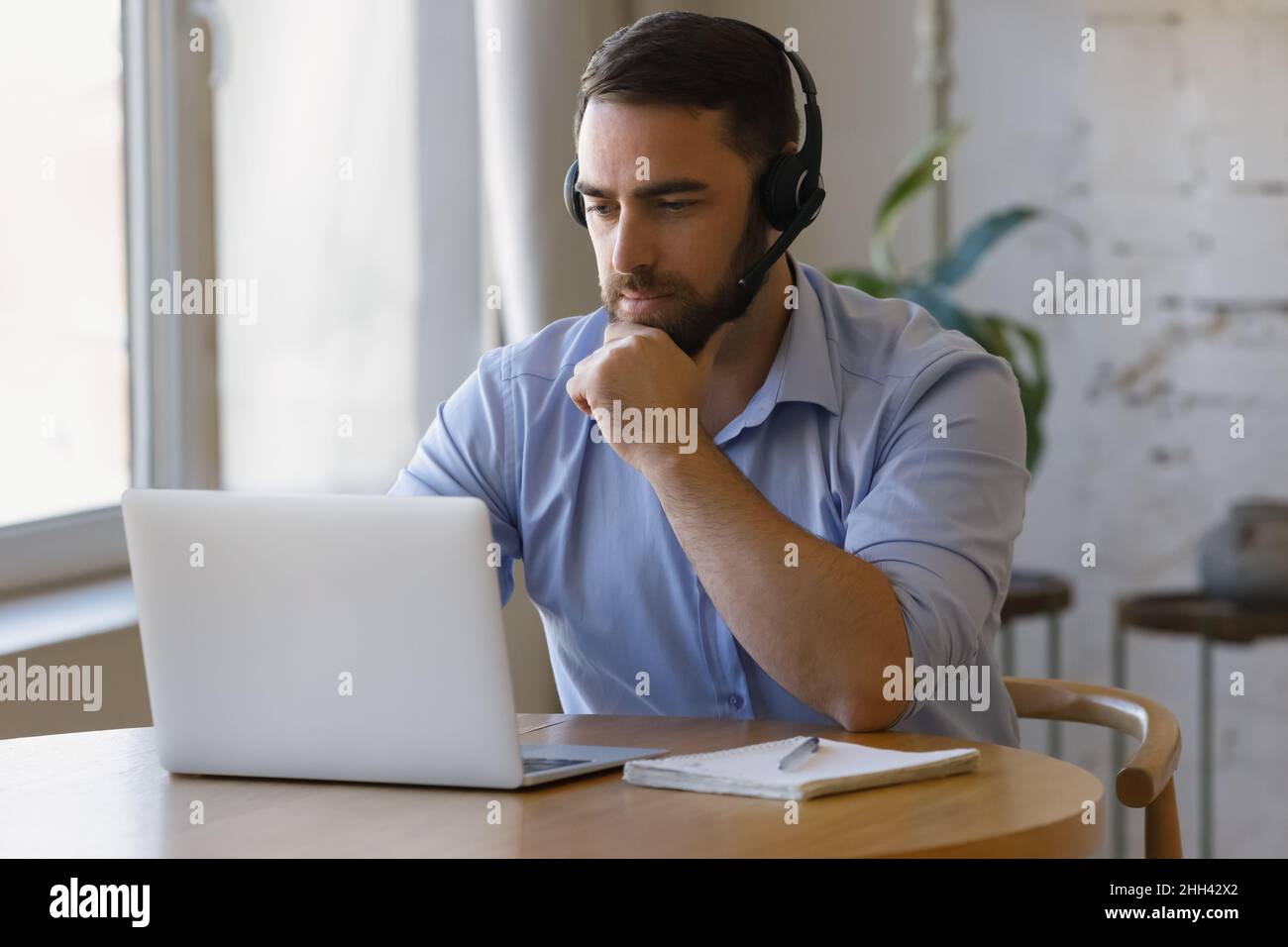 Tausendjähriger Fernarbeiter mit Kopfhörern, der von zu Hause aus arbeitet Stockfoto
