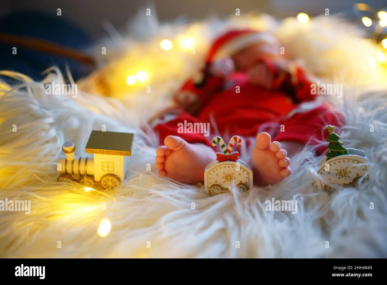 Baby Füße auf einer flauschigen Decke mit Spielzeug, Kind im Weihnachtsmann Kostüm. Selektiver Fokus, geringe Schärfentiefe. Stockfoto