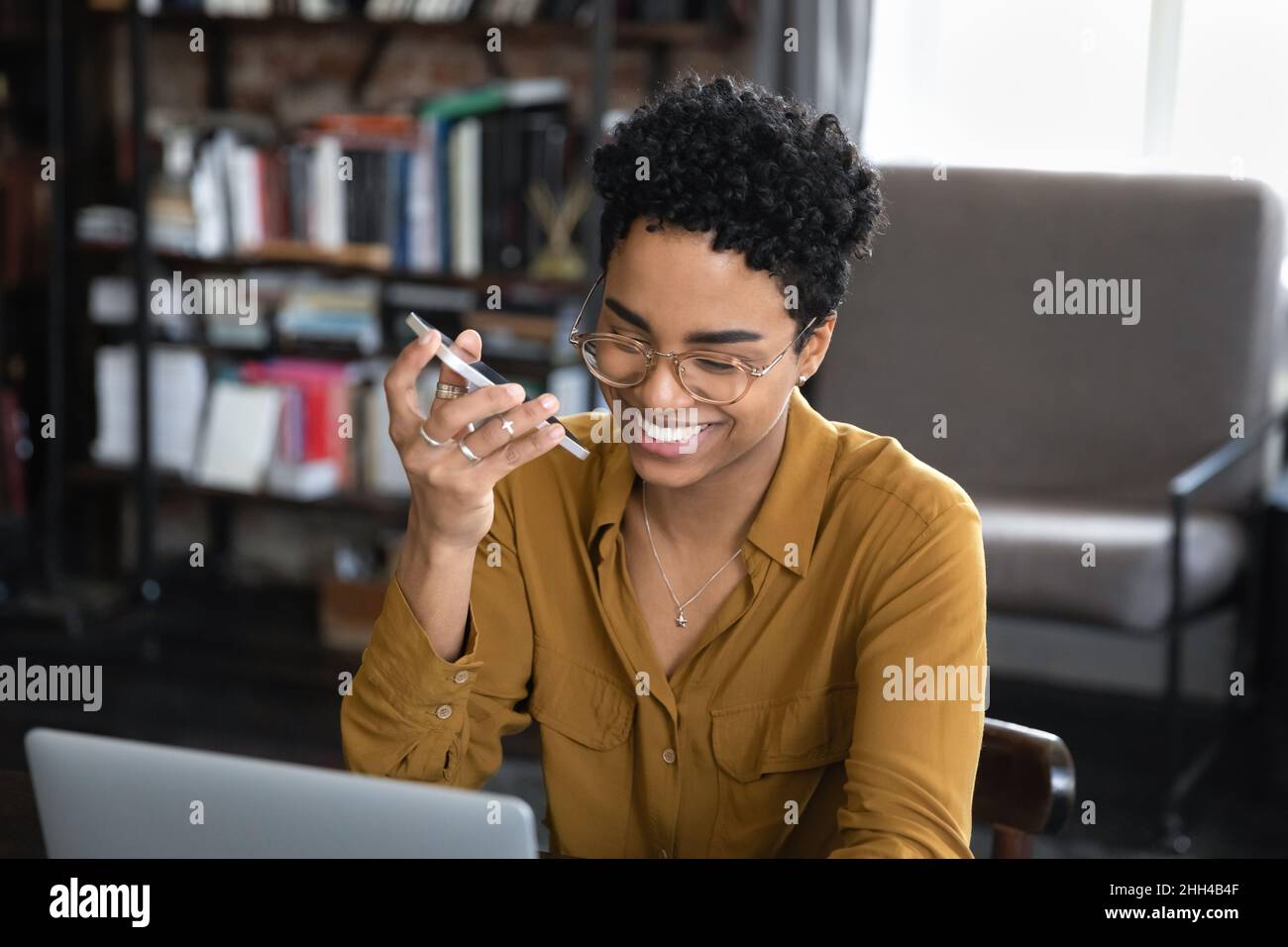 Glückliche afroamerikanische Unternehmerin, die eine Audiobotschaft aufzeichnet Stockfoto