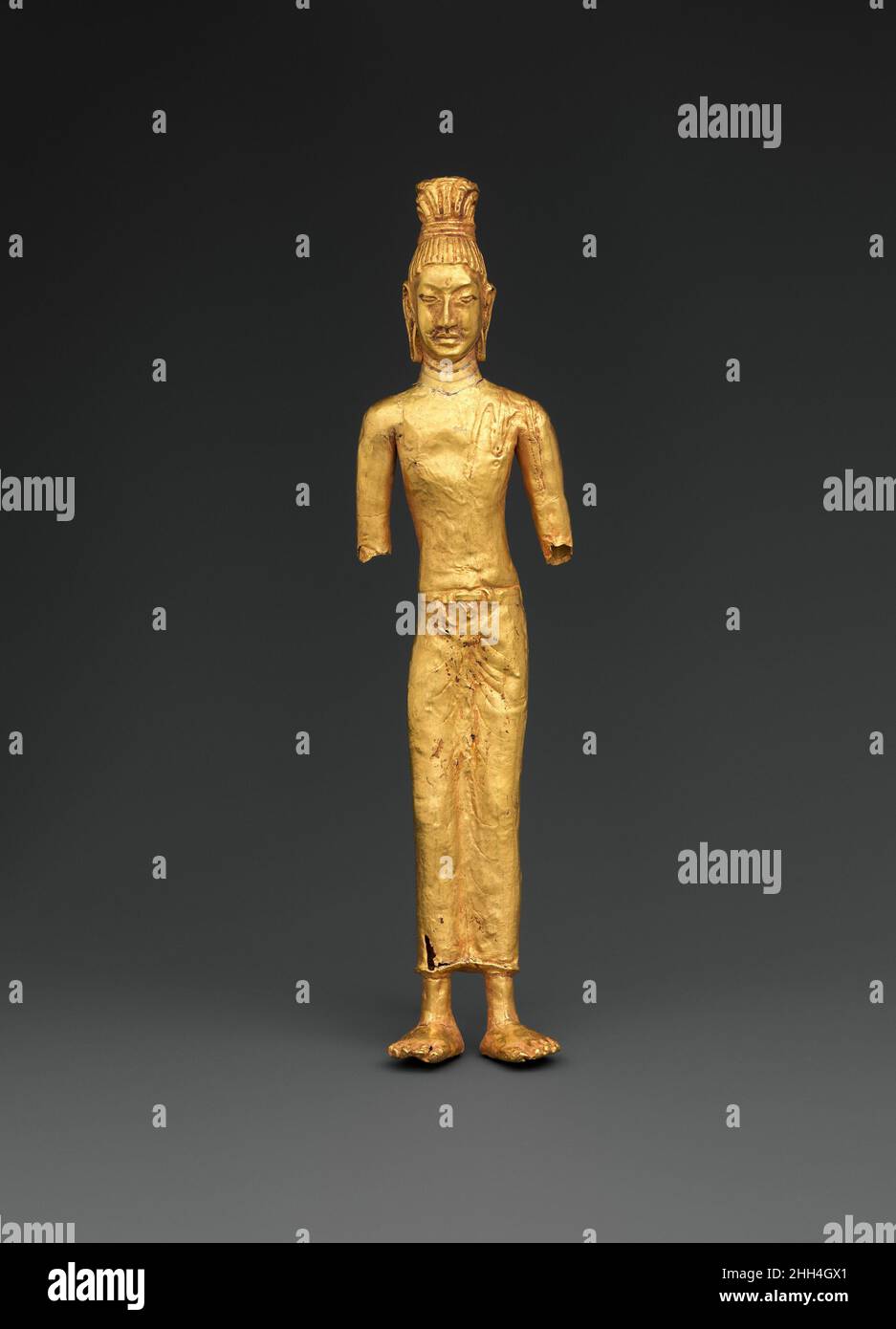 Avalokiteshvara stehend, der Bodhisattva des unendlichen Mitgefühls 8th–9th Jahrhundert wahrscheinlich Thailand oder Kambodscha Diese seltene Gold-Repussé-Darstellung von Avalokiteshvara wurde aus vielen Stücken von passierbarem, bearbeiteten Gold hergestellt. Sowohl die hohe Frisur (Jatamukuta) als auch das Hirtenleder über der linken Schulter der Figur stimmen mit Darstellungen von Avalokiteshvara überein, einem Bodhisattva, der eifrigen Anhängern Mitgefühl und Schutz bot. Der dünne, längliche Körper und die dezente Kleidung stimmen mit der Si-Thep-Produktion überein. Avalokiteshvara stehend, der Bodhisattva des Unendlichen Mitgefühls. Probabl Stockfoto