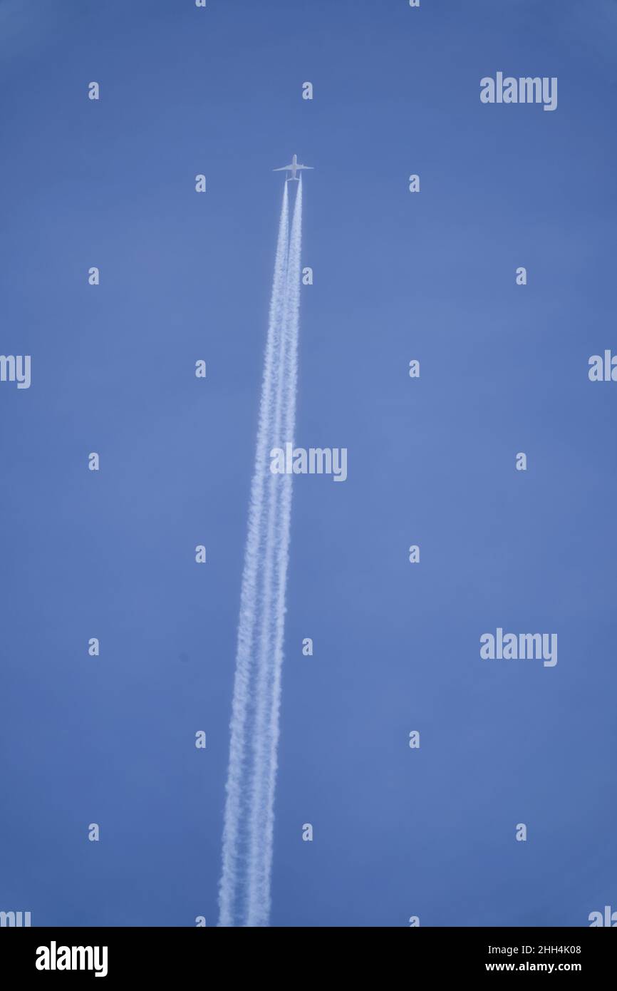 Flugzeug, das am blauen Himmel fliegt und eine Kondensstreifen erzeugt Stockfoto