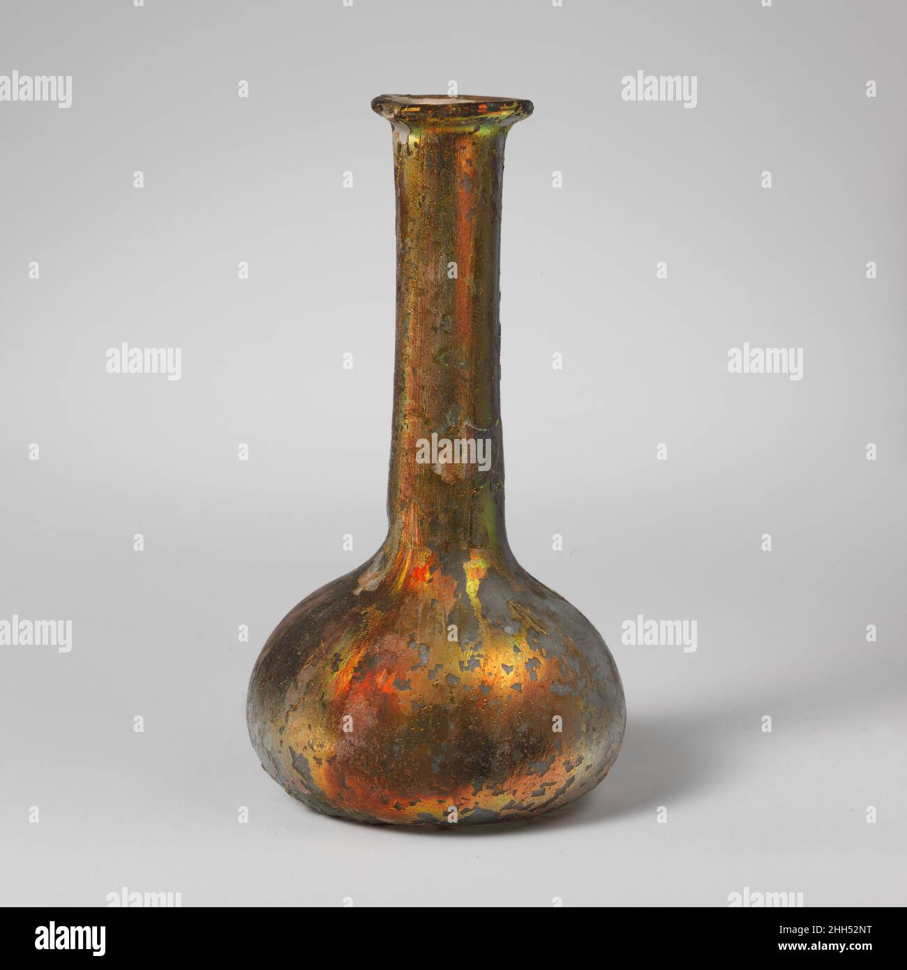 Parfümflasche aus Glas Ende des 1st.–Mitte des 2nd. Jahrhunderts n. Chr. römisch Durchscheinendes blaugrün. Unebener Rand, der nach oben und in den Mund gefaltet und flach gedrückt wird; zylindrischer Hals, der sich leicht nach unten ausdehnt und dann ausgebogen wird, um den hockigen, bauchigen Körper zu verbinden; flacher Boden. Intakt, außer Riss über den unteren und unteren Körper; Viele Nadelstich Blasen; brillant schillernde Verwitterung und Lochfraß.. Parfümflasche aus Glas 239608 Stockfoto