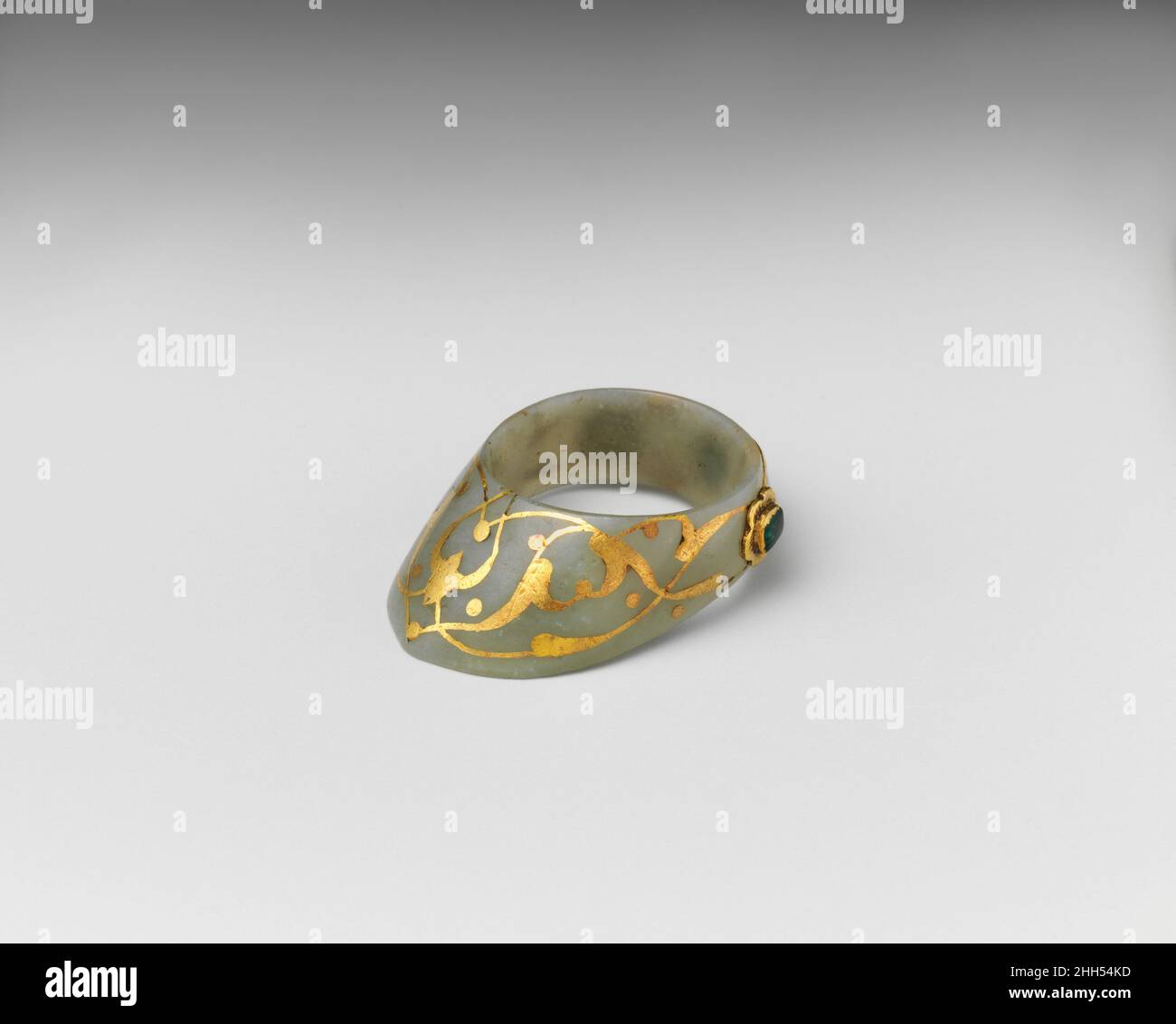 Archer's Thumb Ring 16th–17th Century Turkish Ein Daumenring gab dem Bogenschützen einen festeren Griff der Sehne. Da Bogenschießen als eine edle Sportübung galt, wurden Daumenringe, die oft protzig an am Gürtel hängenden Schnüren getragen wurden, als Symbole eines erhöhten sozialen Status getragen. Dieses Beispiel aus hellgrüner Nephrit-Jade mit Edelsteinen in Goldblatthalterungen ist typisch osmanisch. Ähnliche Ringe sind mit Sultan Süleyman der prächtige (r. 1520–66) und seinen unmittelbaren Nachfolgern. Daumenring des Schützen. Türkisch. 16th–17th Jahrhundert. Jade, Gold, Smaragde, Gelbgold. Bogenschütze Stockfoto