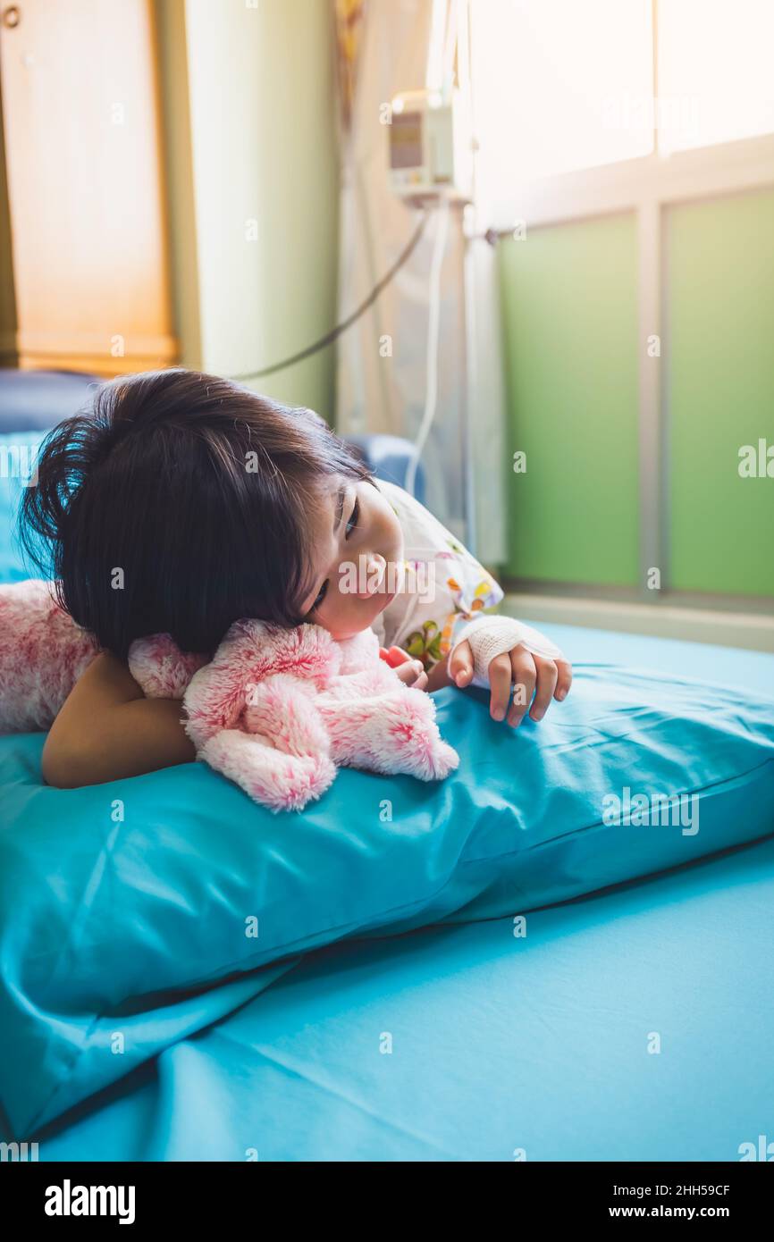 Krankheit Asian Kind im Krankenhaus eingeliefert, während Kochsalzlösung intravenös (IV) zur Hand. Unglückliches Mädchen deprimierend und hoffnungslos mit abwesend gesinnten wegschauen, Kind Stockfoto