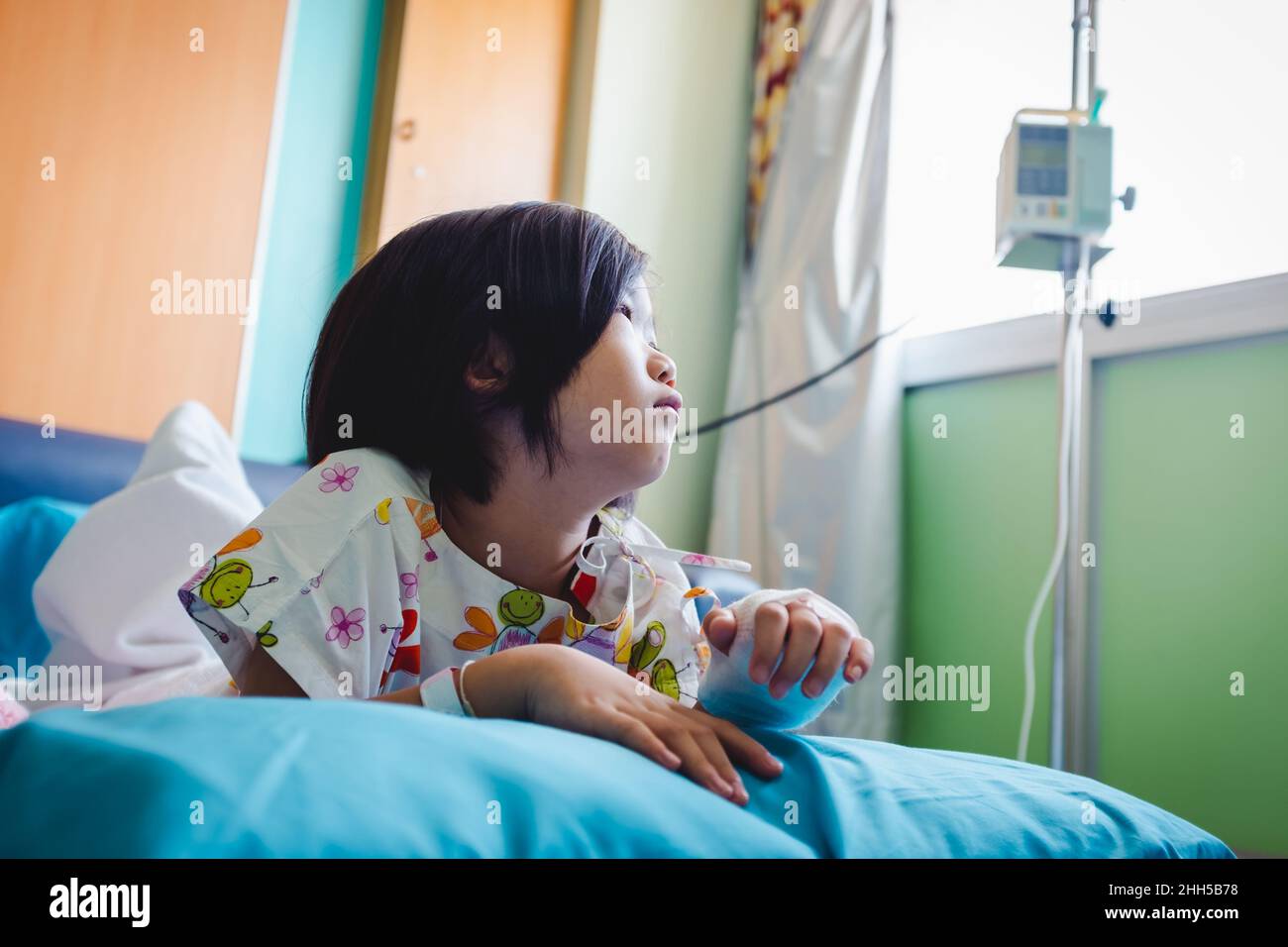 Krankheit Asian Kind im Krankenhaus eingeliefert, während Kochsalzlösung intravenös (IV) zur Hand. Unglückliches Mädchen deprimierend und hoffnungslos mit abwesend gesinnten Blick nach draußen, Stockfoto