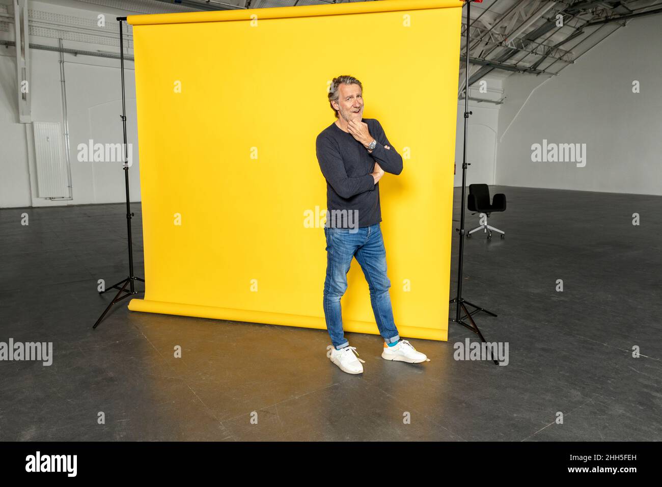 Geschäftsmann mit der Hand am Kinn vor gelbem Hintergrund Stockfoto