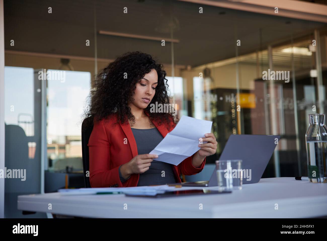 Geschäftsfrau beim Lesen eines Papierdokuments am Arbeitsplatz Stockfoto