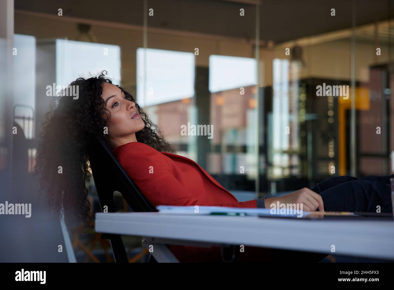 Geschäftsfrau träumen, während sie am Arbeitsplatz auf einem Stuhl sitzt Stockfoto