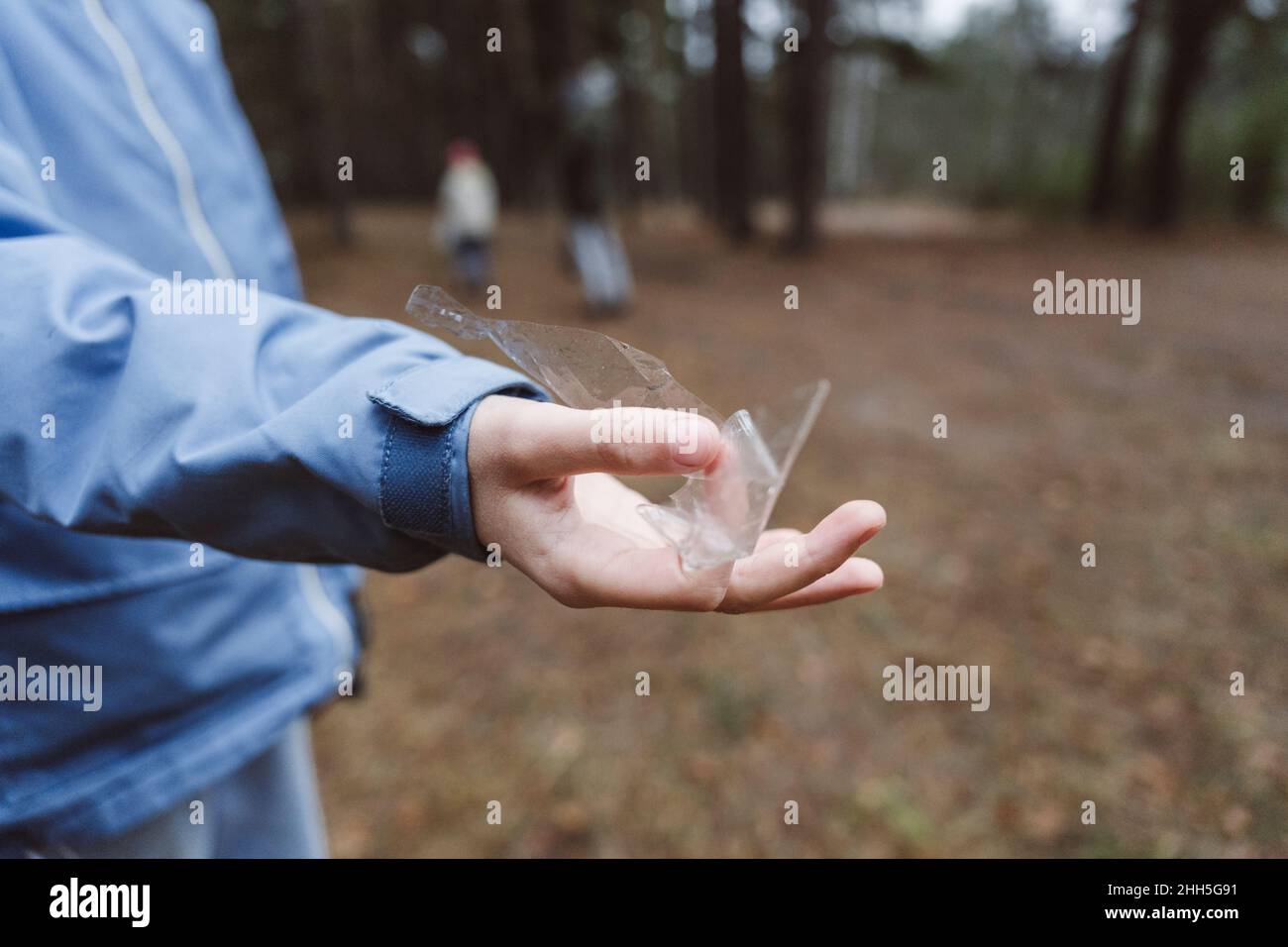 Junge Hand hält Plastikmüll im Wald Stockfoto