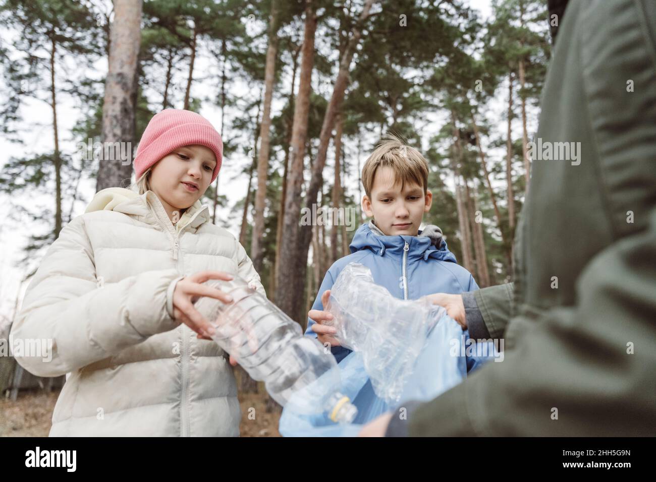 Vater mit Kindern sammeln Plastikmüll im Wald Stockfoto