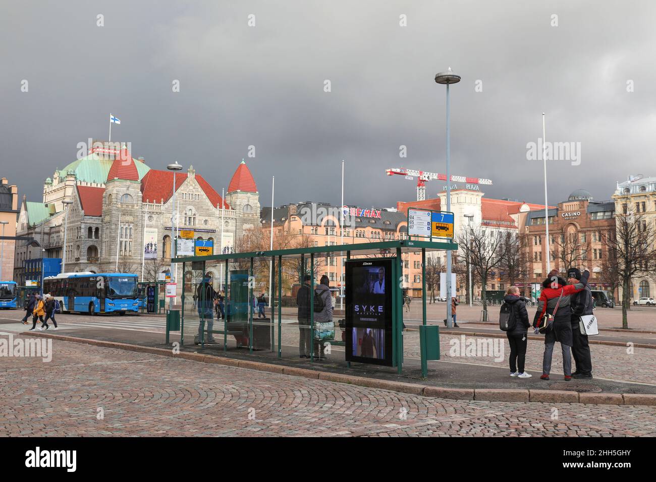 An einer Bushaltestelle auf dem Helsinki Railway Square warten Menschen auf den Bus.im November 2021 wurden in Finnland alle Covid-19-Beschränkungen aufgehoben. Die Leute laufen ohne Masken herum und alle öffentlichen Plätze waren offen. Stockfoto