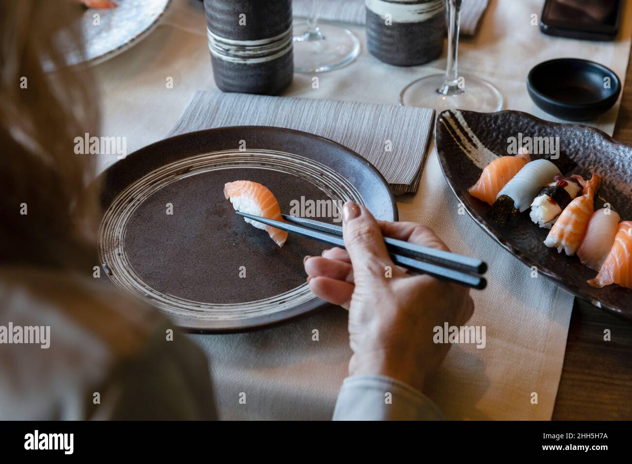 Frau hält Sushi mit Essstäbchen im Restaurant Stockfoto