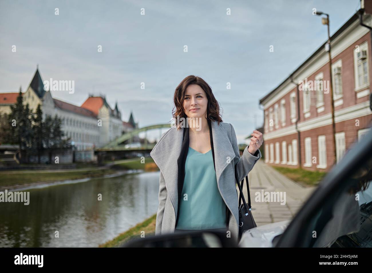 Frau in einer Jacke, die mit dem Auto auf dem Fußweg eine Geldbörse trägt Stockfoto