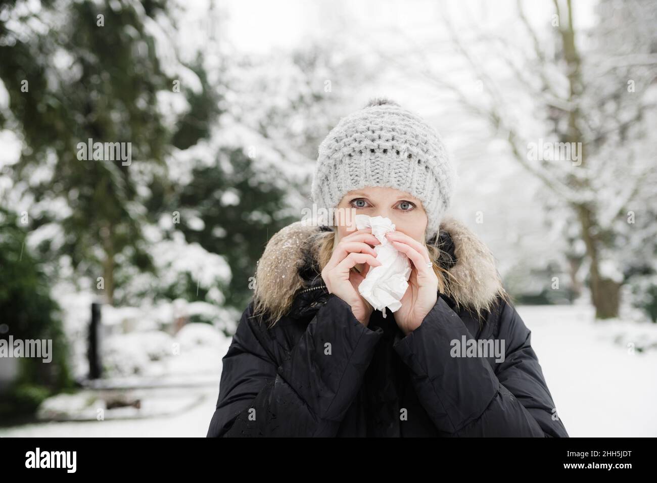 Frau bläst Nase mit Gesichtsgewebe im Winter Park Stockfoto