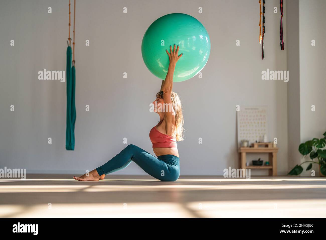 Frau, die mit einem Fitnessball im Yoga-Studio sitzt Stockfoto