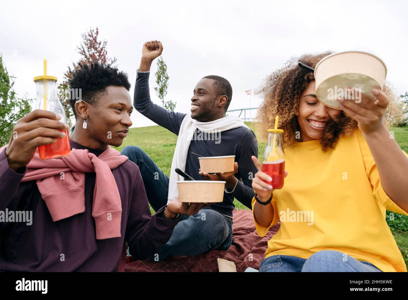 Junge Freunde unterhalten sich und essen beim Picknick Stockfoto