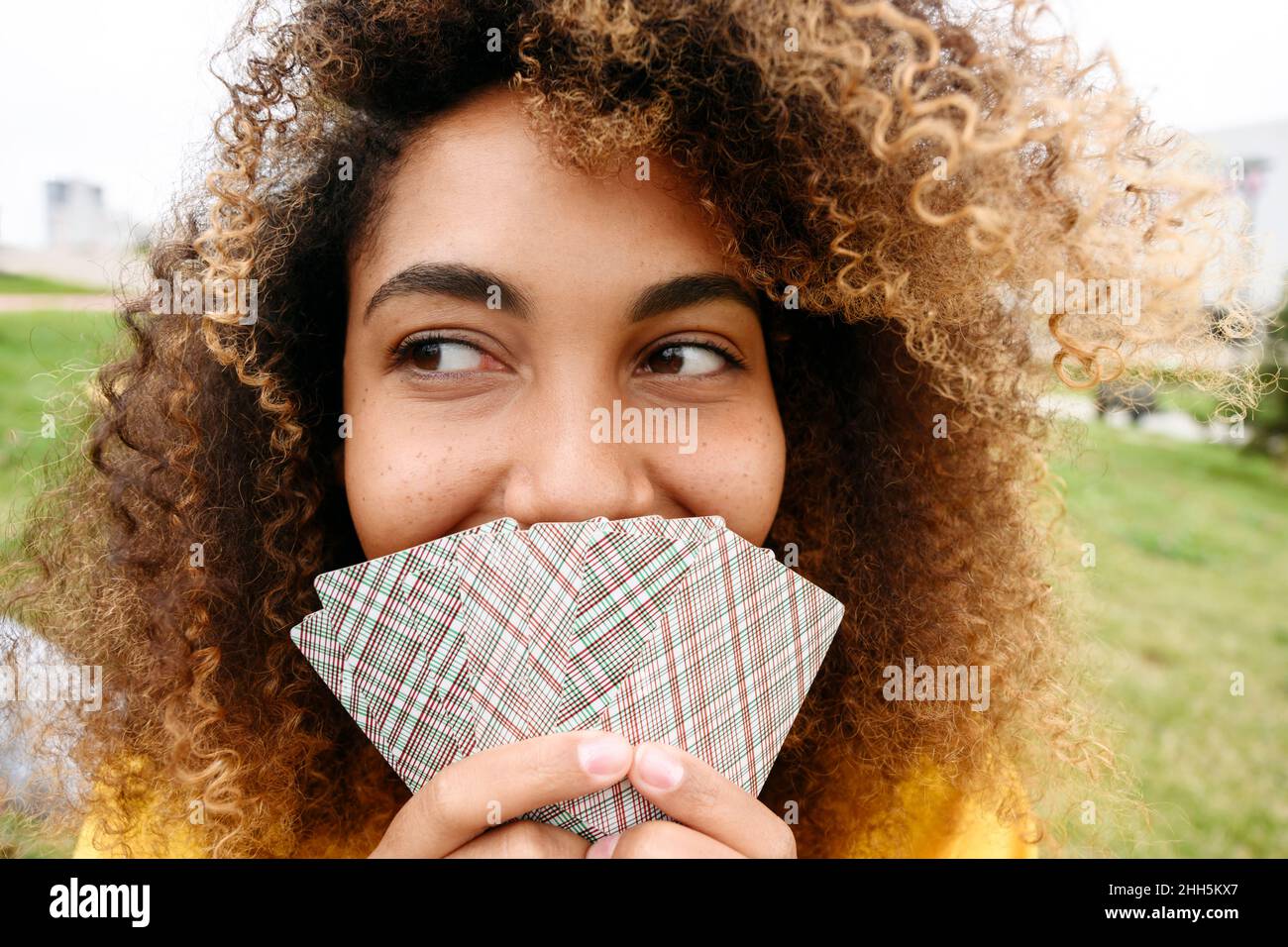 Junge Frau bedeckt den Mund mit Spielkarten Stockfoto