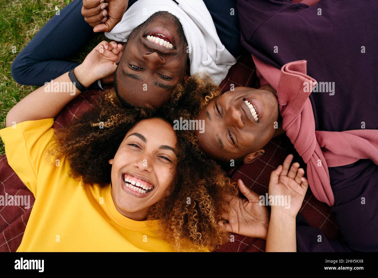 Fröhliche junge Freunde liegen auf der Decke im Park Stockfoto