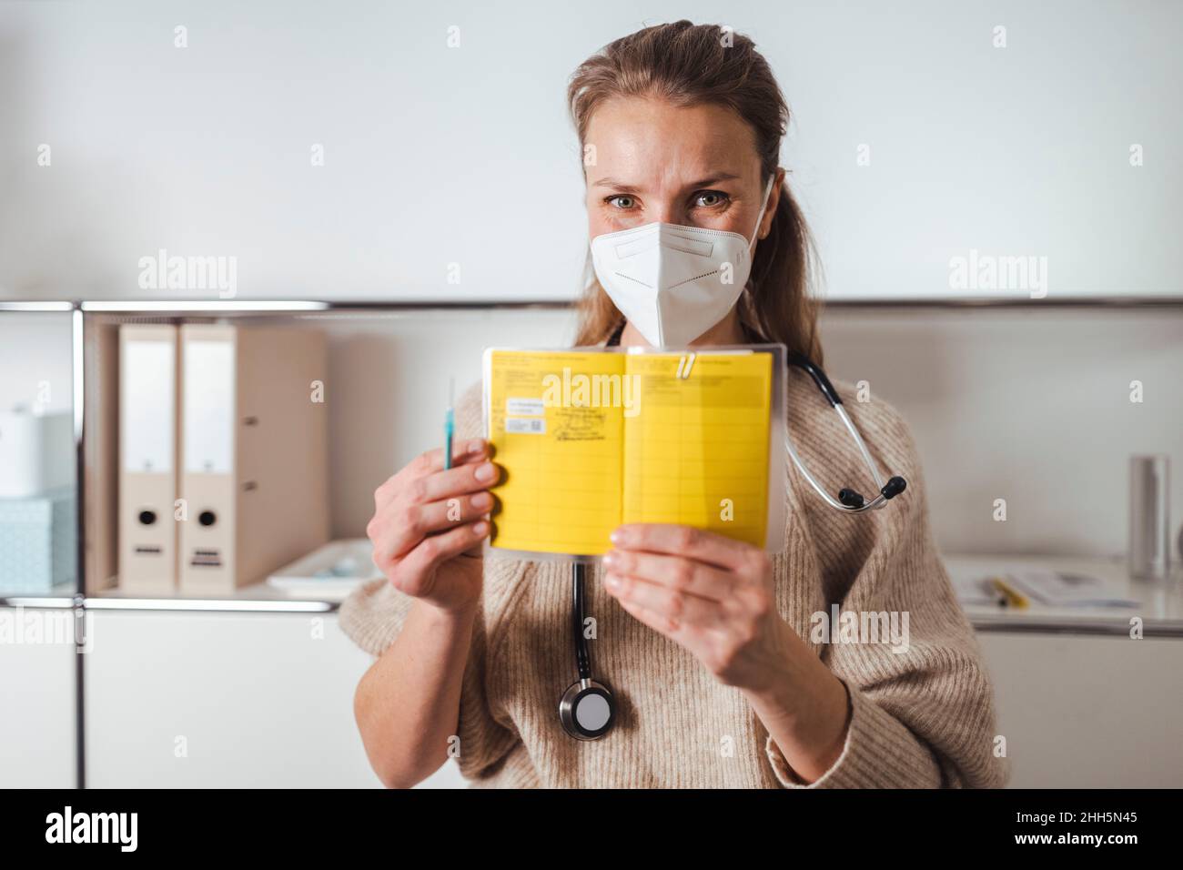 Arzt mit Schutzmaske mit Impfpass Stockfoto