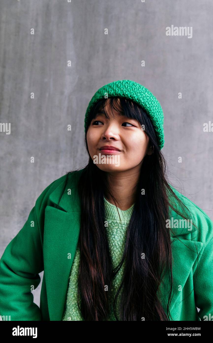 Junge Frau trägt grünen Wintermantel und Strickmütze Stockfoto