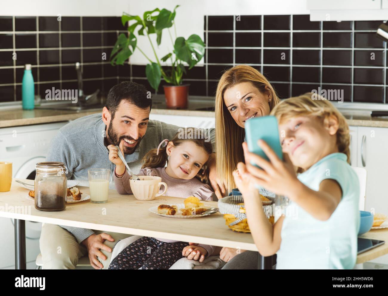 Junge, der Selfie mit einer glücklichen Familie am Frühstückstisch macht Stockfoto