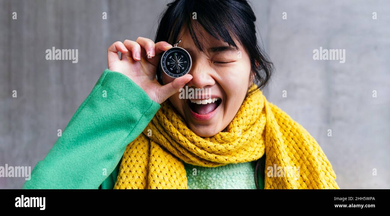 Fröhliche Frau, die das Auge mit einem Kompass bedeckt Stockfoto