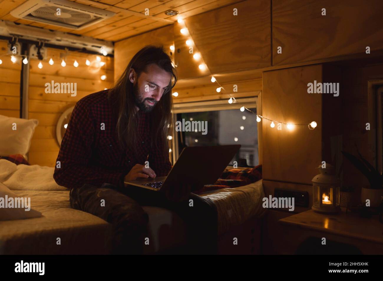Junger Mann, der in den Weihnachtsferien einen Laptop in einem Kleinbus benutzt Stockfoto
