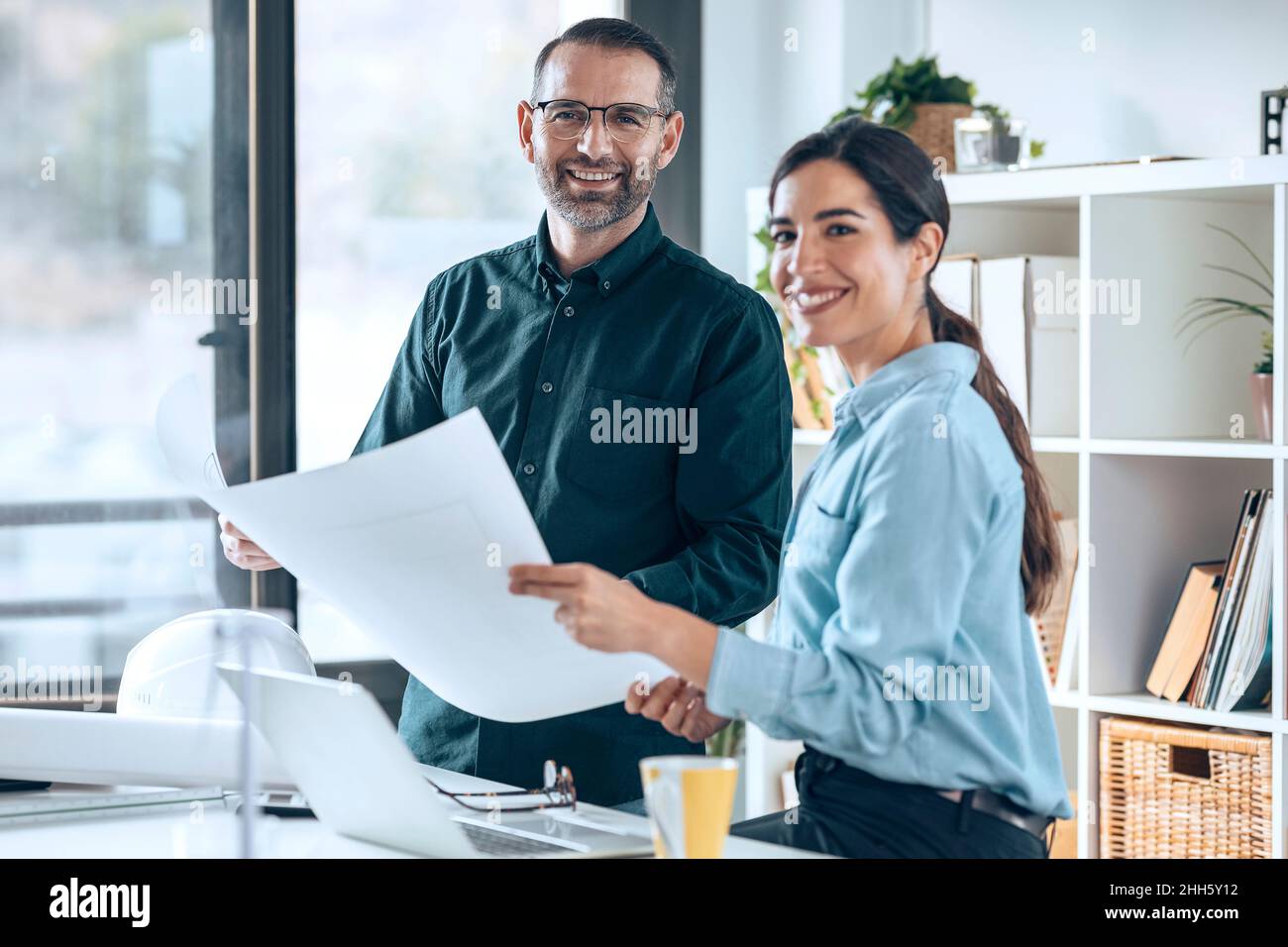 Lächelnde Architekten mit Grundriß im Büro Stockfoto