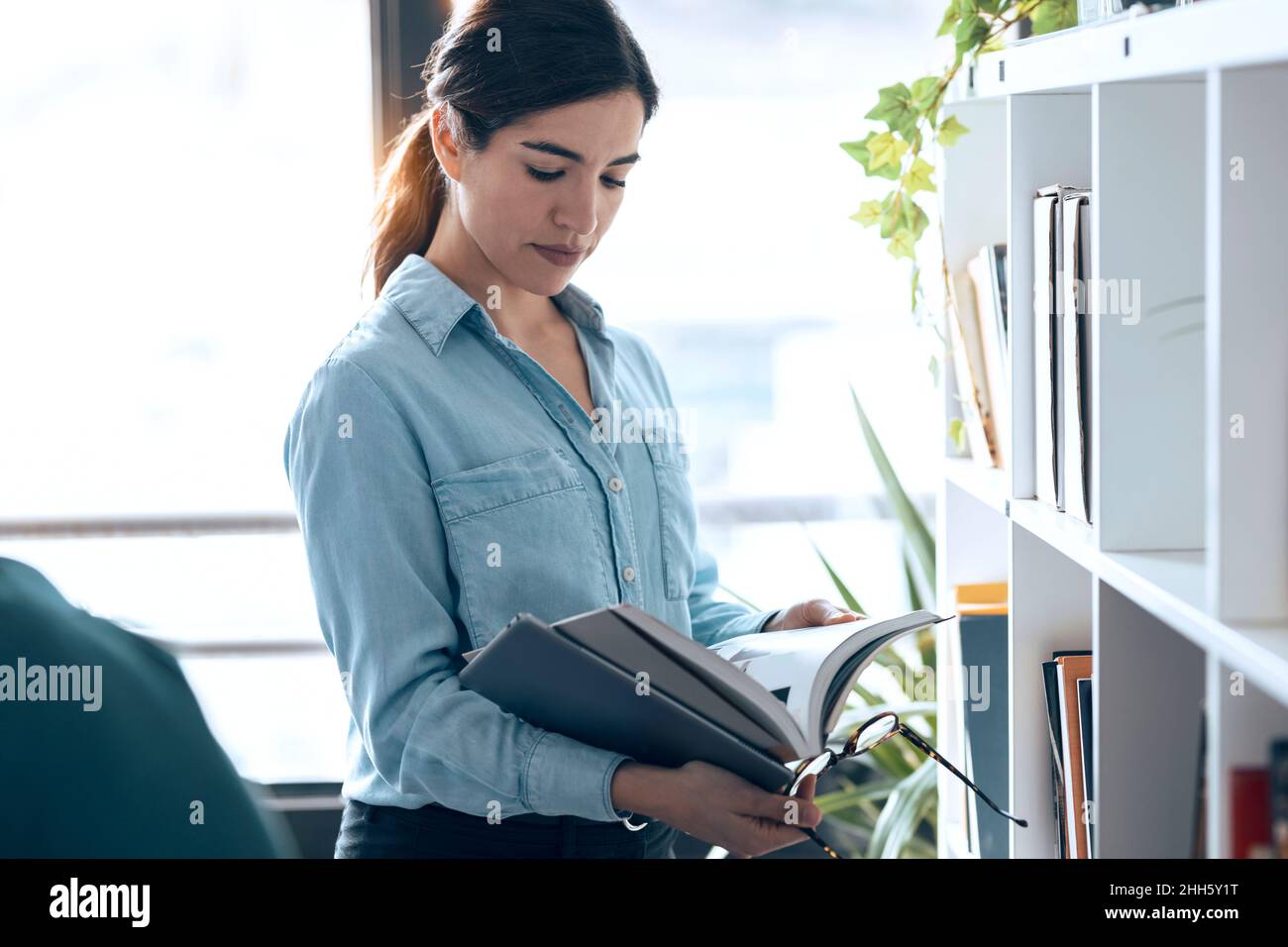 Architekt liest Buch für Regal in einem kleinen Büro Stockfoto