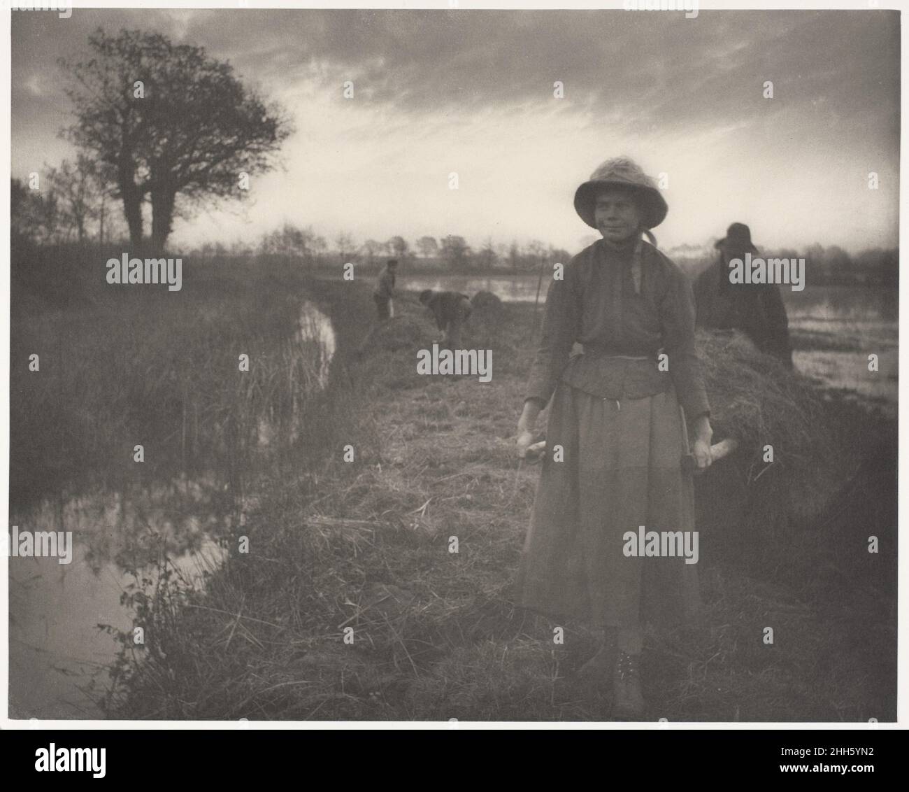 Poling the Marsh Hay 1886 Peter Henry Emerson Brite, geborene Cuba P. H. Emersons Buch "Life and Landscape on the Norfolk Broads", in dem dieses Bild eines von vierzig Tafeln war, war die erste Demonstration des Naturalismus, den er für die Fotografie befürwortete. Während H. P. Robinson das gleiche Ziel wie sein ideologisches Gegenteil anstrebte - die Anerkennung der Fotografie als bildende Kunst -- Emerson zog seine Themen nicht aus literarischen Erzählungen, sondern aus einer zugleich höchst persönlichen und anthropologischen Untersuchung der Umwelt und der täglichen Rituale des ländlichen Lebens in East Anglia, den sumpfigen coas Stockfoto
