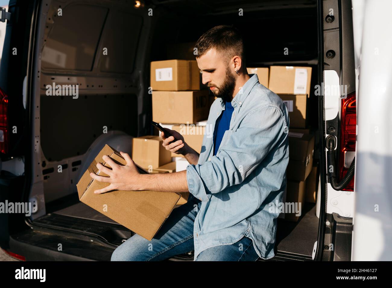 Zustellperson scannt Paket im Lieferwagen Stockfoto