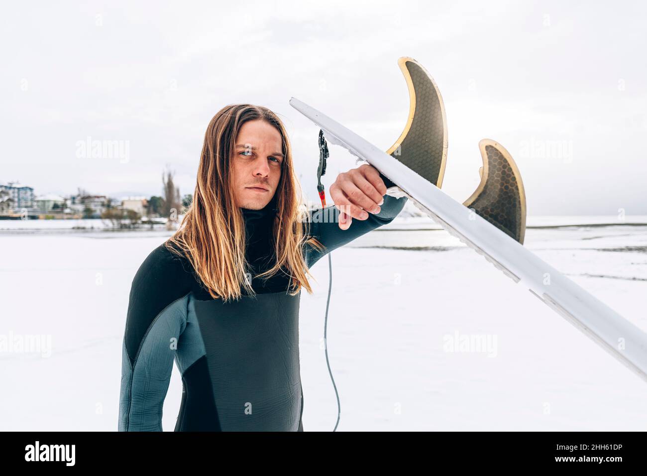 Selbstbewusster Mann mit Surfbrett im Winterurlaub Stockfoto